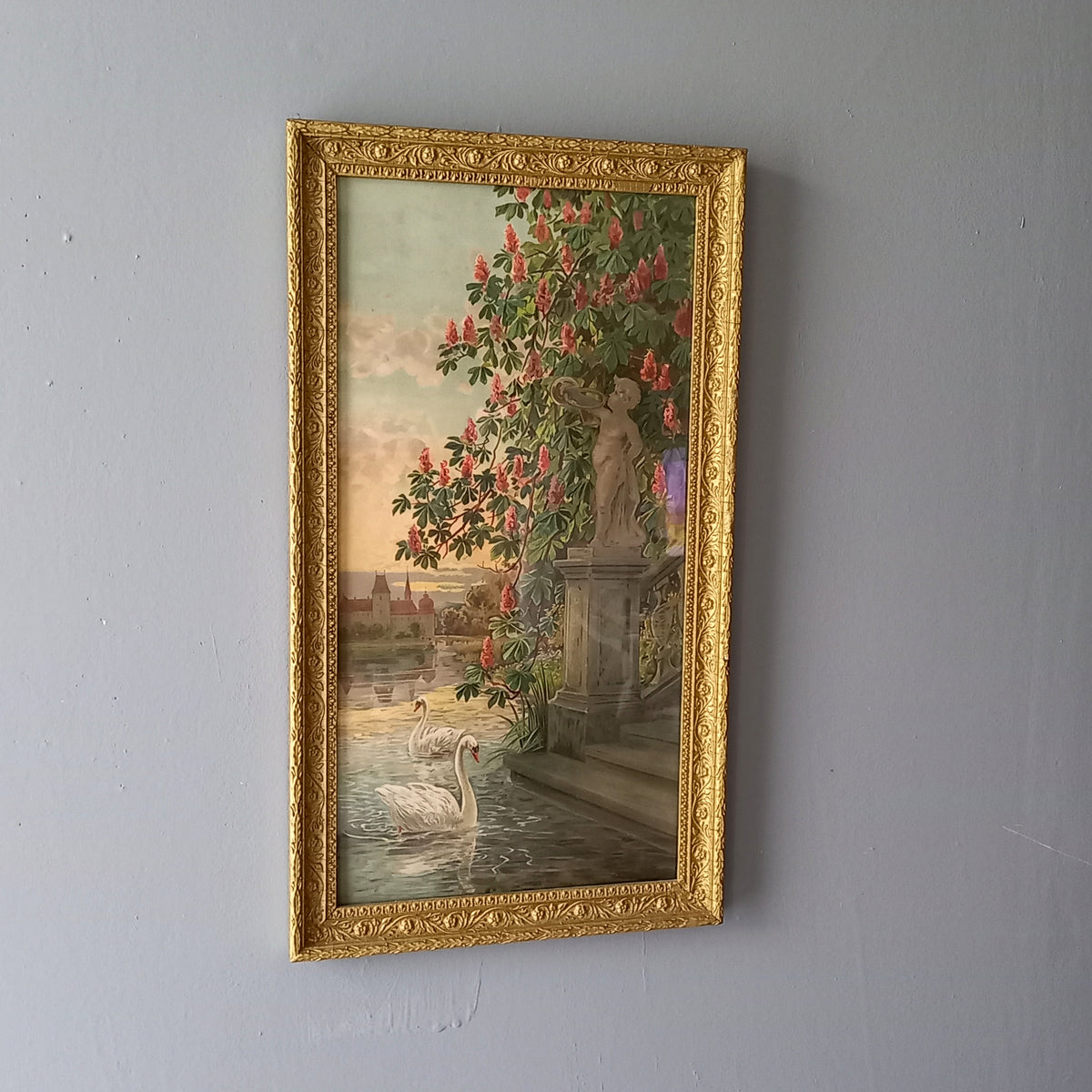 Decorative painting with a gold frame of a garden scene with flowers and a statue.