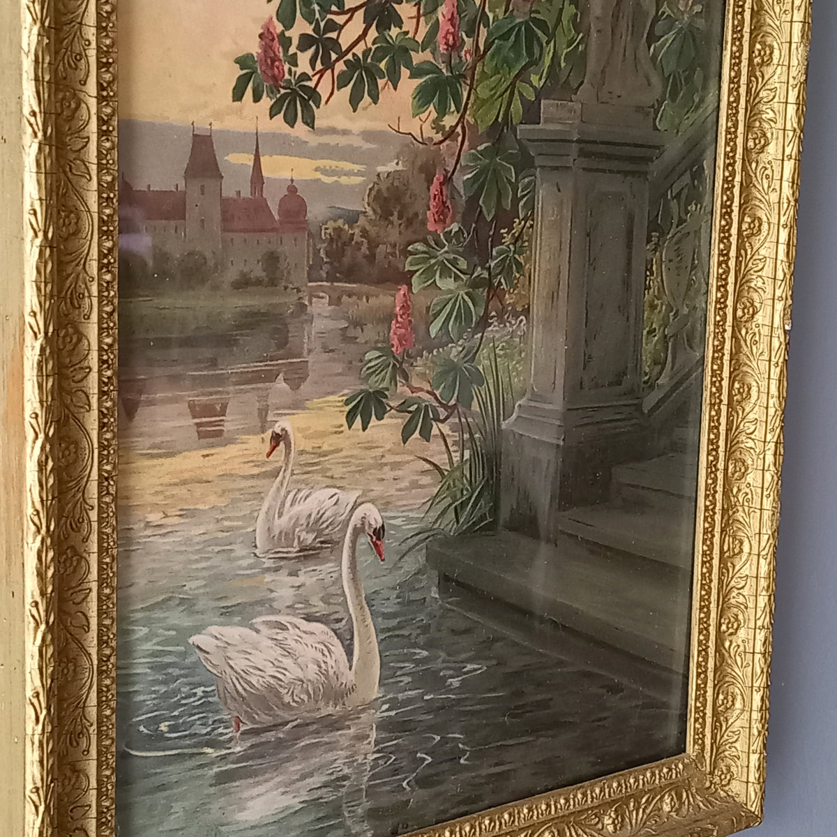Decorative painting of swans on water with a castle in the background, framed in gold.