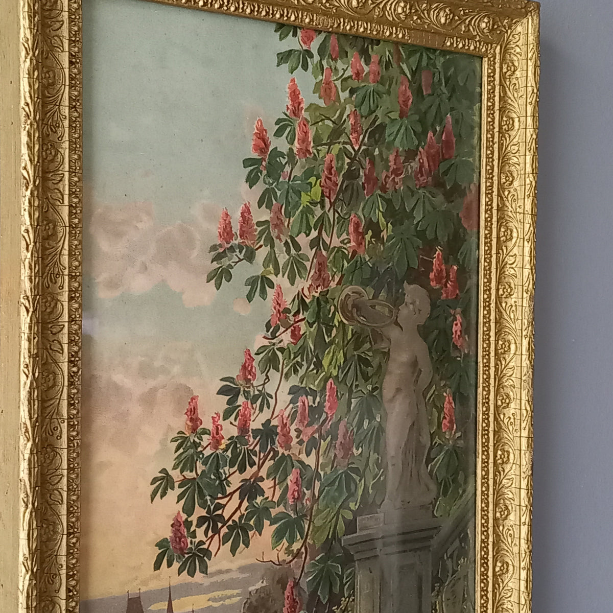 Decorative painting with floral elements and a gold frame on a gray wall.