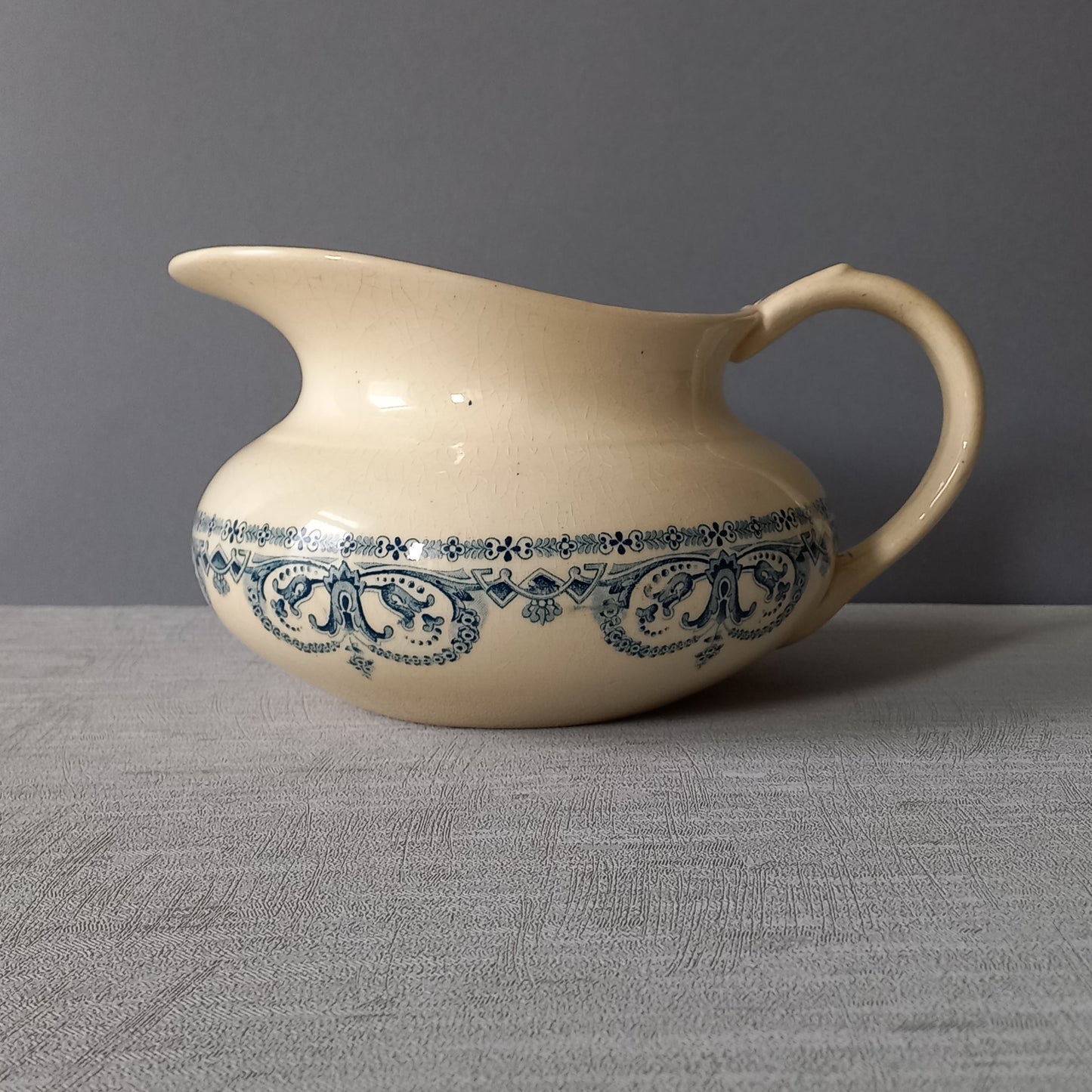 A beautiful French antique jug/pitcher, once used to pour water in a bowl for washing yourself, these days wonderful home decor - many people use them as bathroom decor.

This particular piece is in a lovely shade of off-white/cream with a dark blue transfer pattern - a very stylish and eye-catching piece of ironstone.