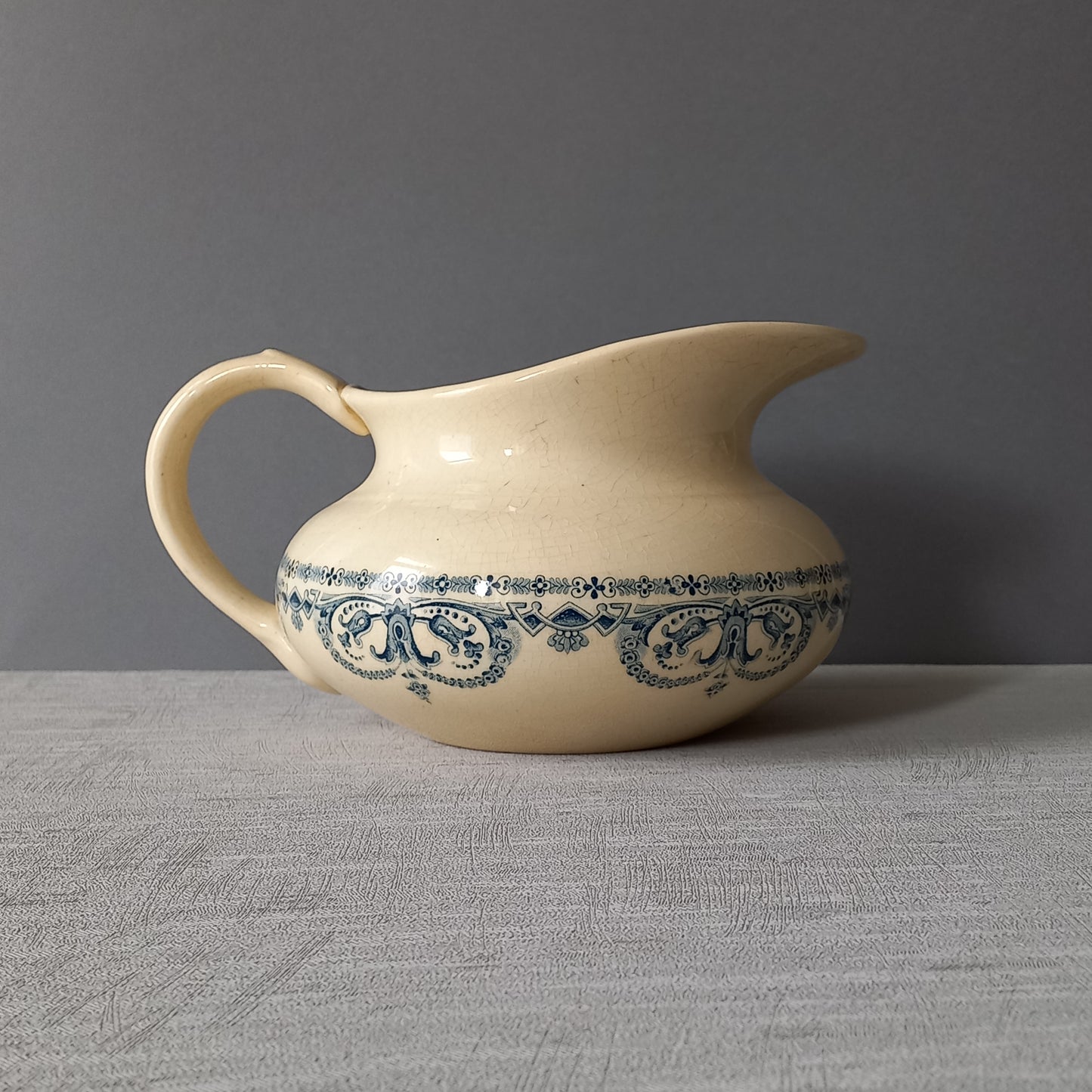 A beautiful French antique jug/pitcher, once used to pour water in a bowl for washing yourself, these days wonderful home decor - many people use them as bathroom decor.

This particular piece is in a lovely shade of off-white/cream with a dark blue transfer pattern - a very stylish and eye-catching piece of ironstone.