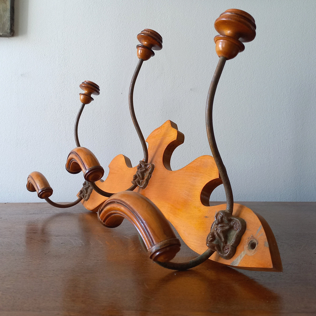 A stunning French vintage coat and hat rack with a decorative wooden wall-mounted rack holding 3 metal hooks, each hook having 2 turned wooden pegs for a hat and coat.

In summary a decorative and practical piece of vintage wall decor for any interior.