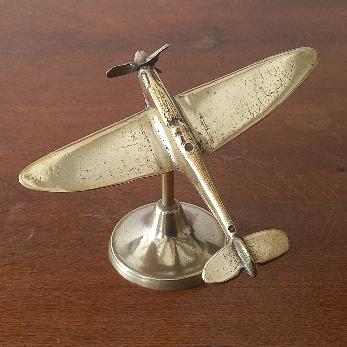 Brass airplane model on a wooden surface