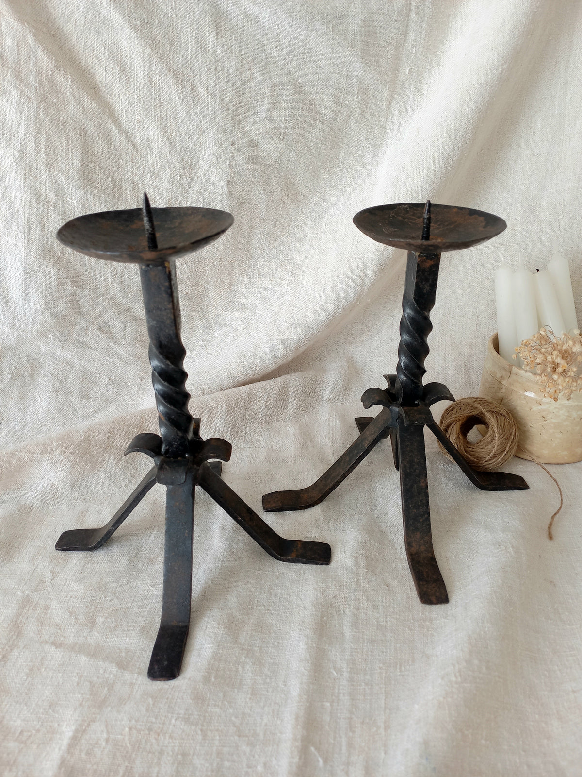 Pair of black wrought iron candle holders on a white fabric background