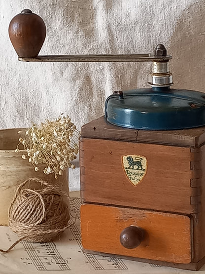 Vintage wooden coffee grinder with a brand logo on a textured surface with string and pins.