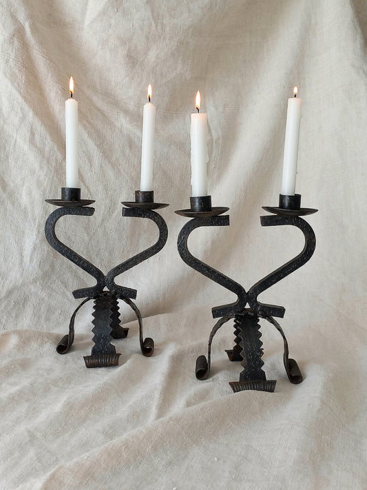 Pair of black cast iron candle holders with white candles on a textured beige background