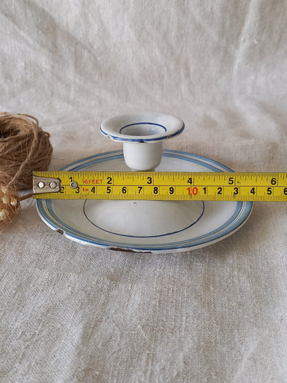 White enamel candle holder with blue rim on a textured beige surface with twine and dried flowers and a tape-measure for reference.