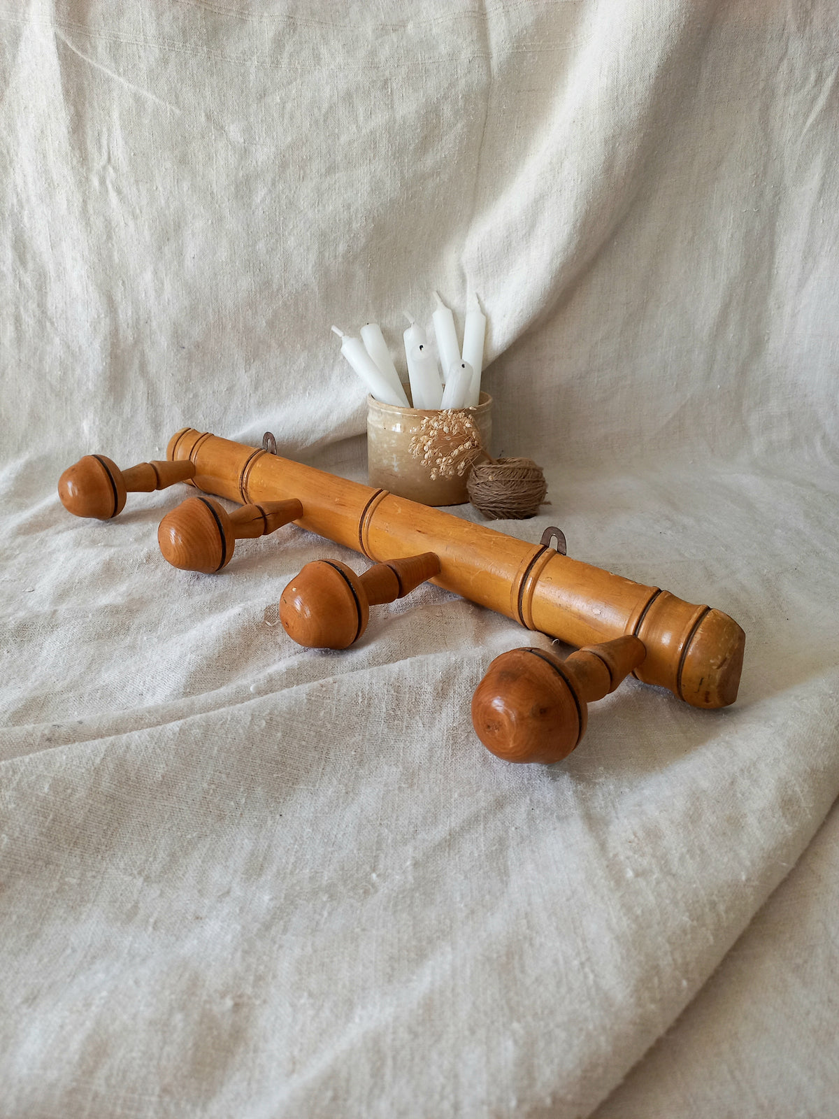 4 peg faux bamboo wooden coat rack on a textured white fabric background