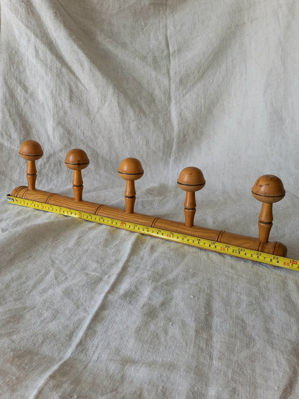 Wooden garment rack with five knobs on a textured fabric background