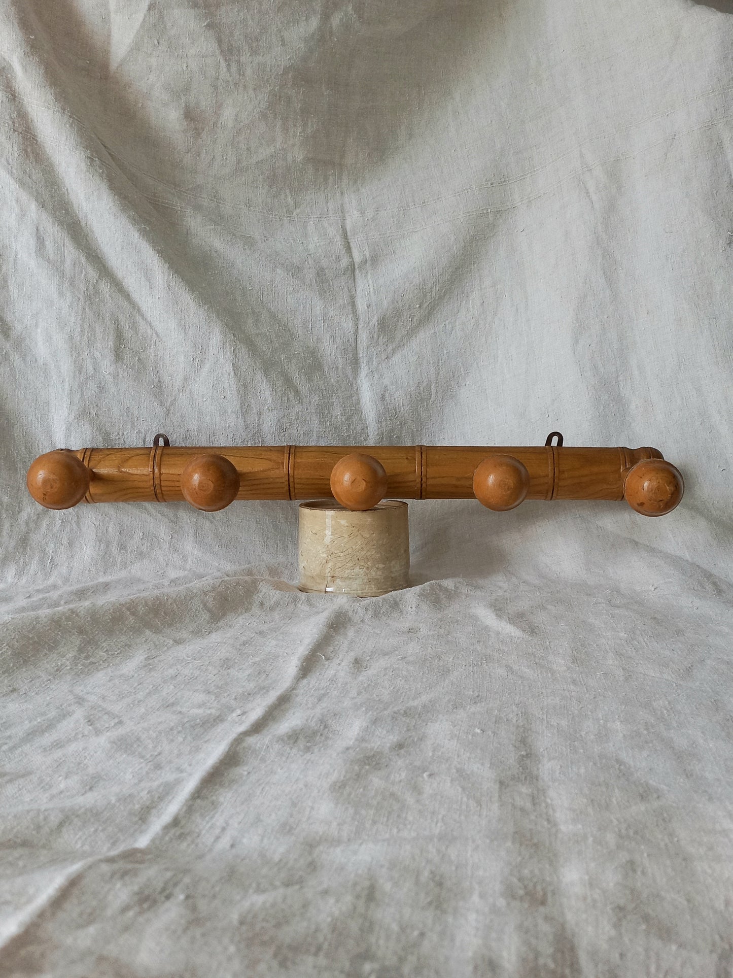 Wooden coat rack with spherical ends on a textured fabric background