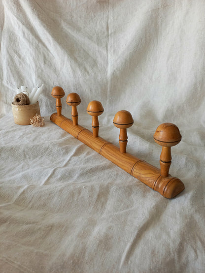 Wooden garment rack with spherical ends on a textured white fabric background