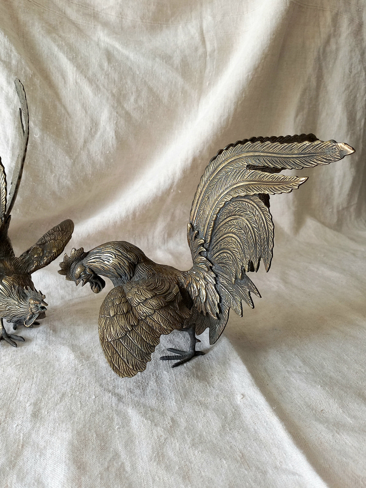 Bronze cockerel figurine on a textured white fabric background