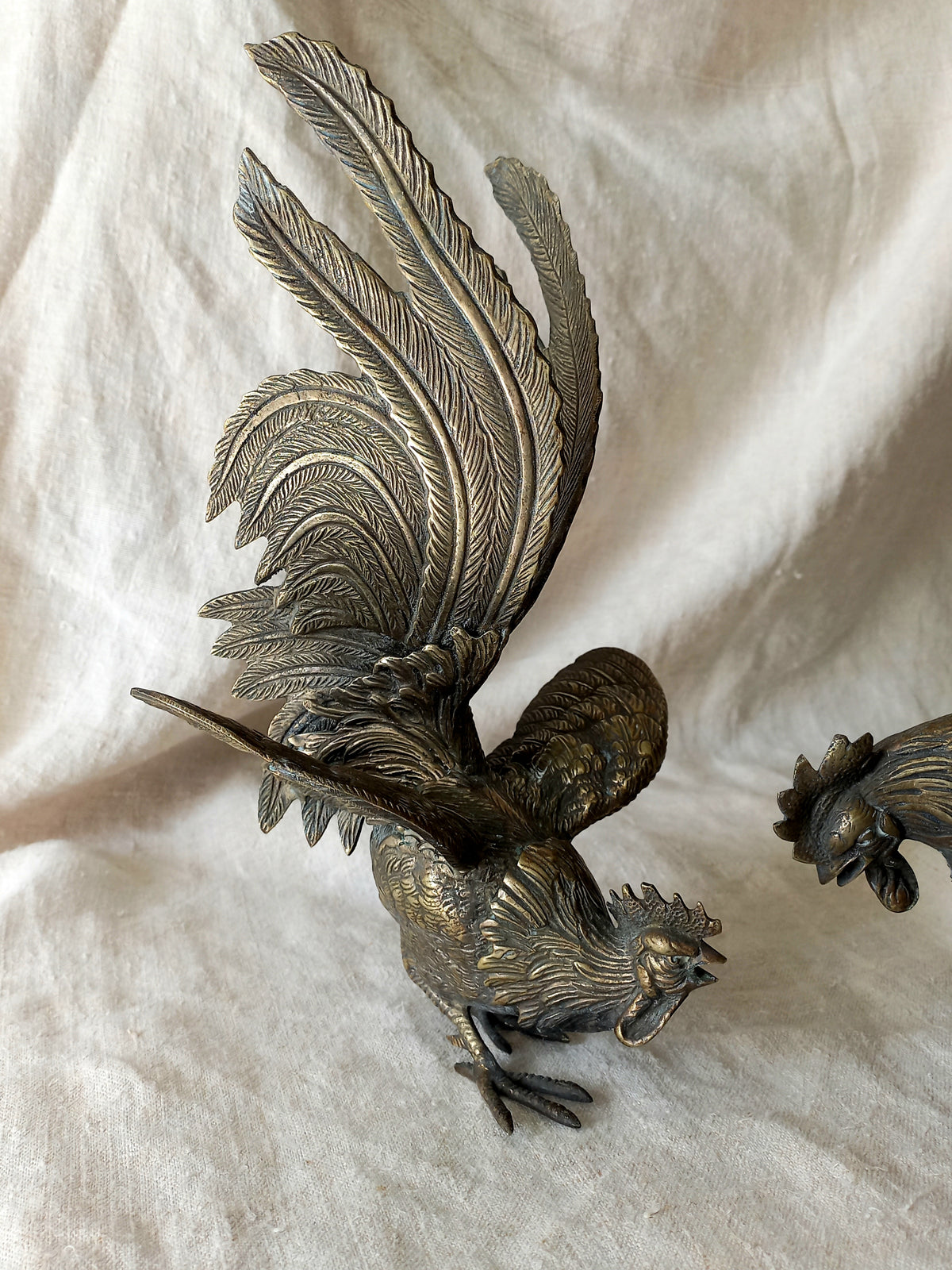 Bronze rooster sculpture on a white fabric background