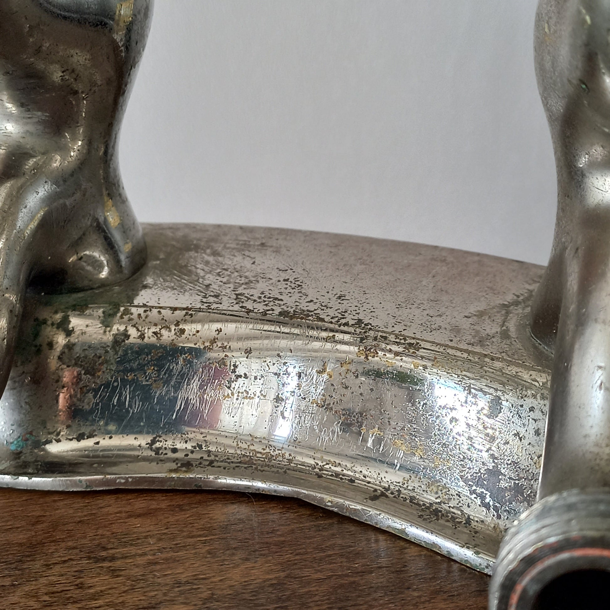 Close-up of a vintage metal faucet on a wooden background with visible wear and tear 