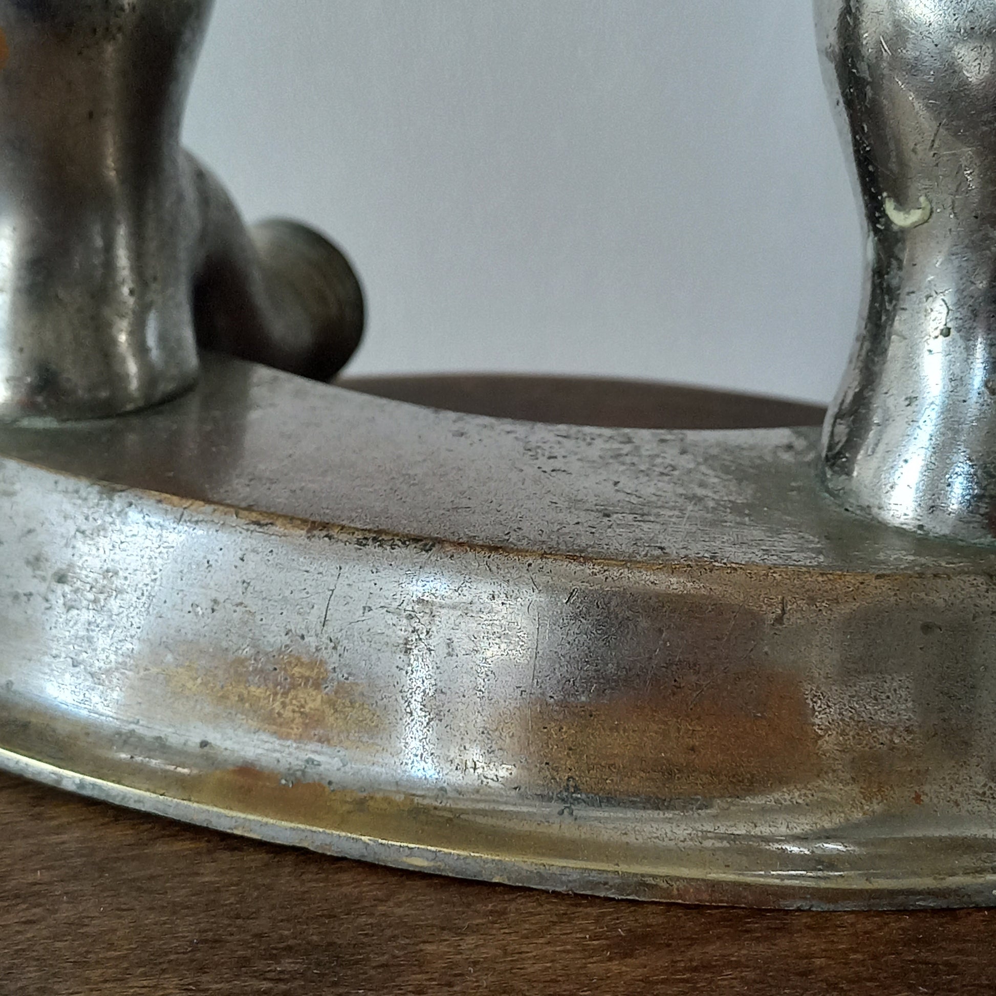 Close-up of a vintage metal faucet on a wooden background with visible wear and tear 