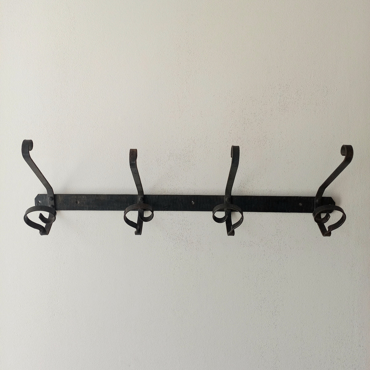 A large French vintage metal coat and hat rack for 4 coats and hats, a hand-made piece that is sturdy and can be screwed directly to your wall using the holes already in the wall bracket. The colour of the coat rack is a pleasing worn satin black with traces of gold showing through in places which give it a nice aged appearance.