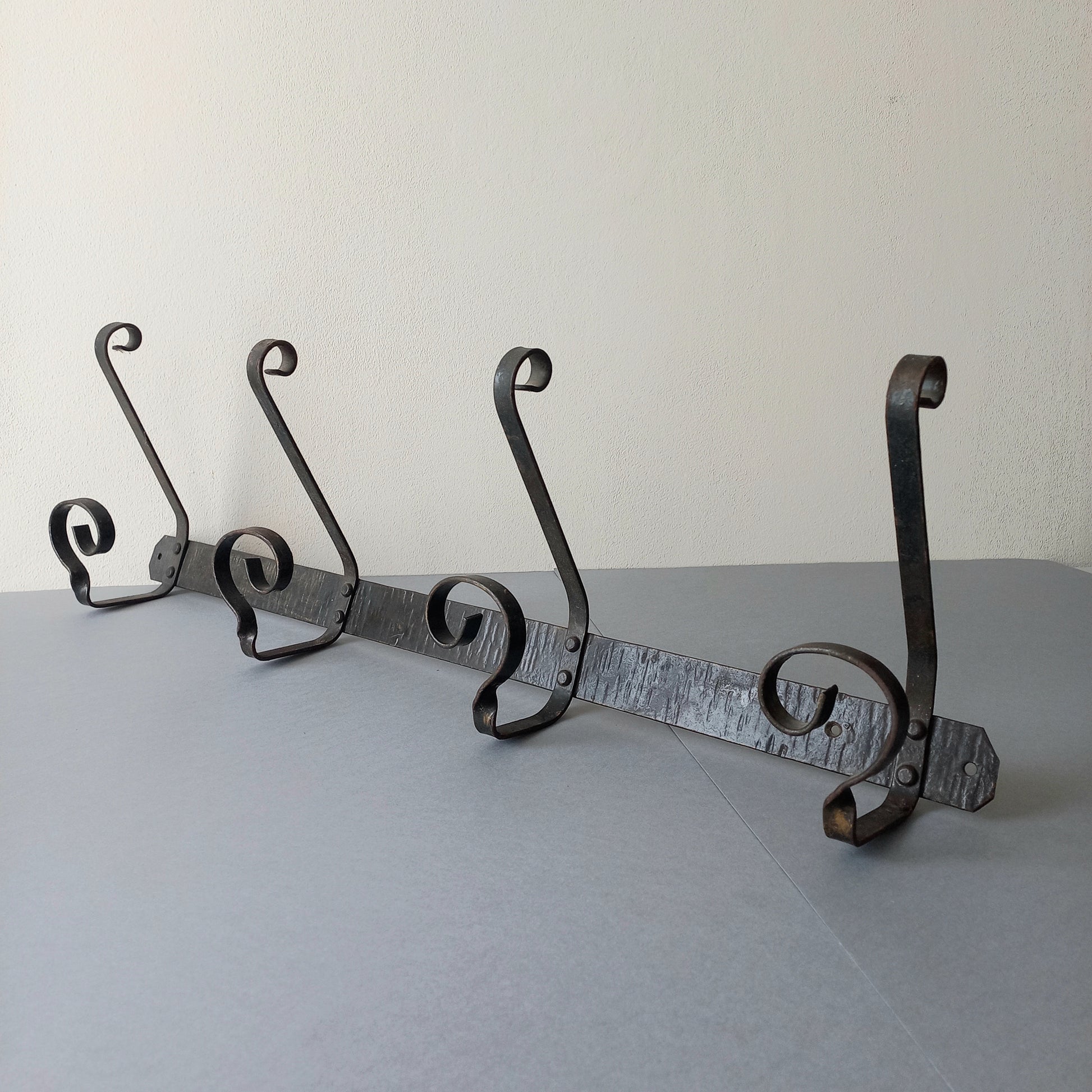 A large French vintage metal coat and hat rack for 4 coats and hats, a hand-made piece that is sturdy and can be screwed directly to your wall using the holes already in the wall bracket. The colour of the coat rack is a pleasing worn satin black with traces of gold showing through in places which give it a nice aged appearance.