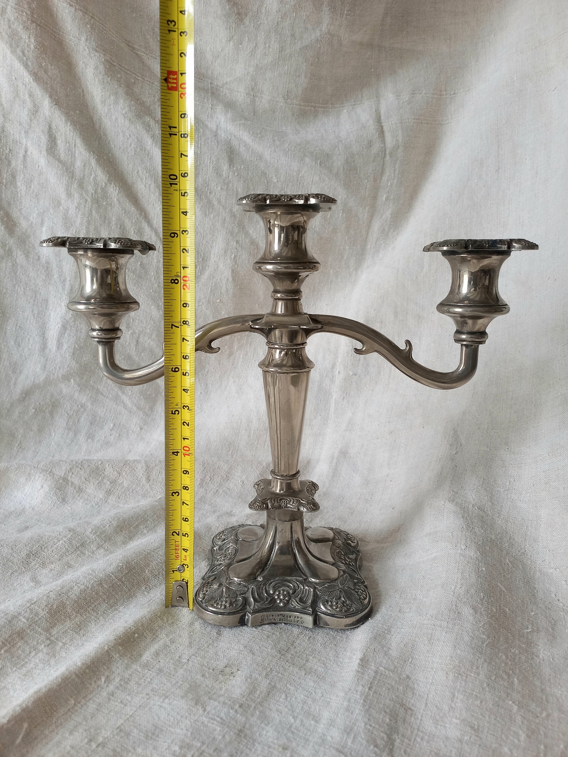 Silver candelabra with a measuring tape on a textured white background