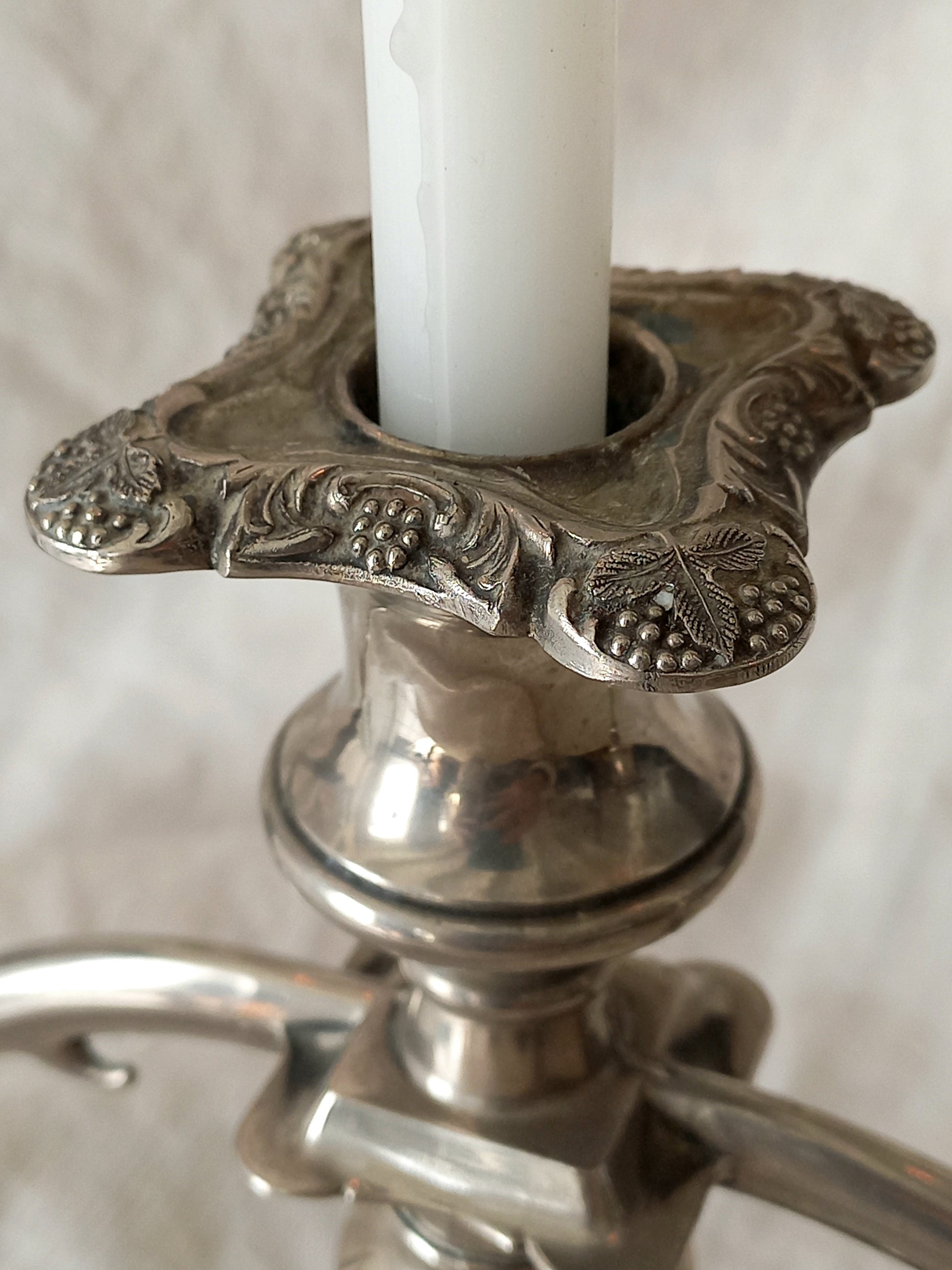 Decorative silver candle holder with a white candle on a neutral background