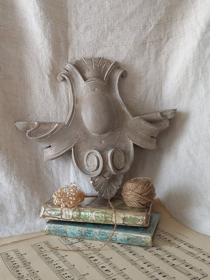 A French antique decorative carved wooden pediment that has been tastefully painted and worn to give an attractive shabby chic finish.